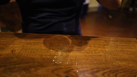el hombre coloca el vaso de bebida en la mesa de madera
