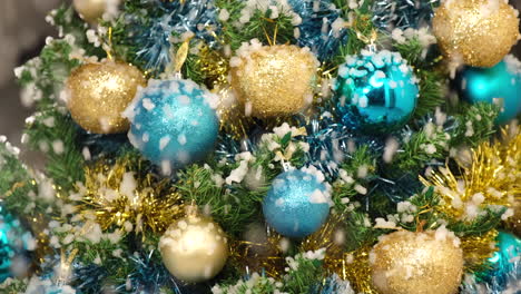 la nieve del árbol de navidad cae sobre una bola dorada y azul en la noche de invierno