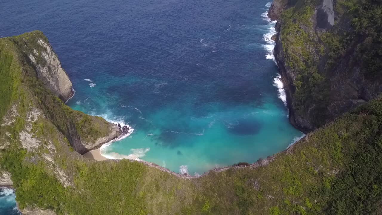 Dramatische Luftaufnahme: Langsames Hochneigen eines hohen Drohnenflugs über kristallklarem türkisfarbenem Wasser am mystischen Kelingking Beach auf Nusa Penida in Bali, Indonesien