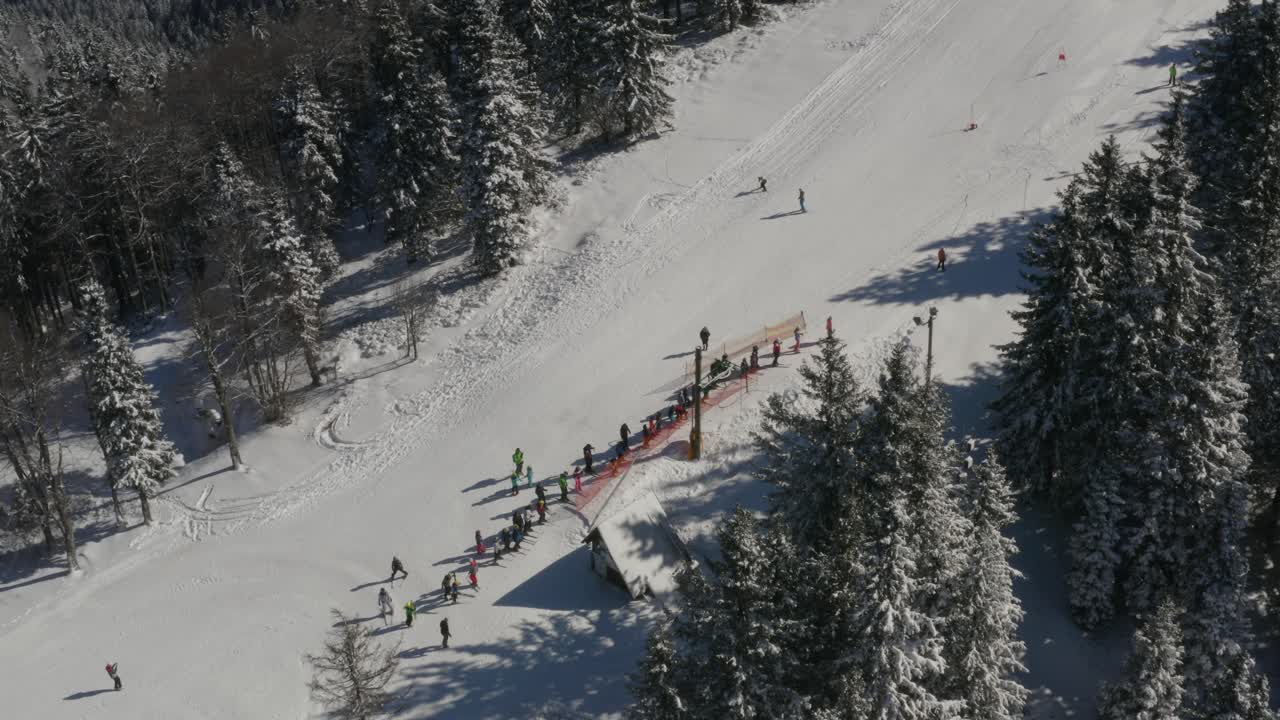 Sciatori si radunano su una pista nel resort Kope in Slovenia, nelle montagne del Pohorje, ripresa aerea con tilt up