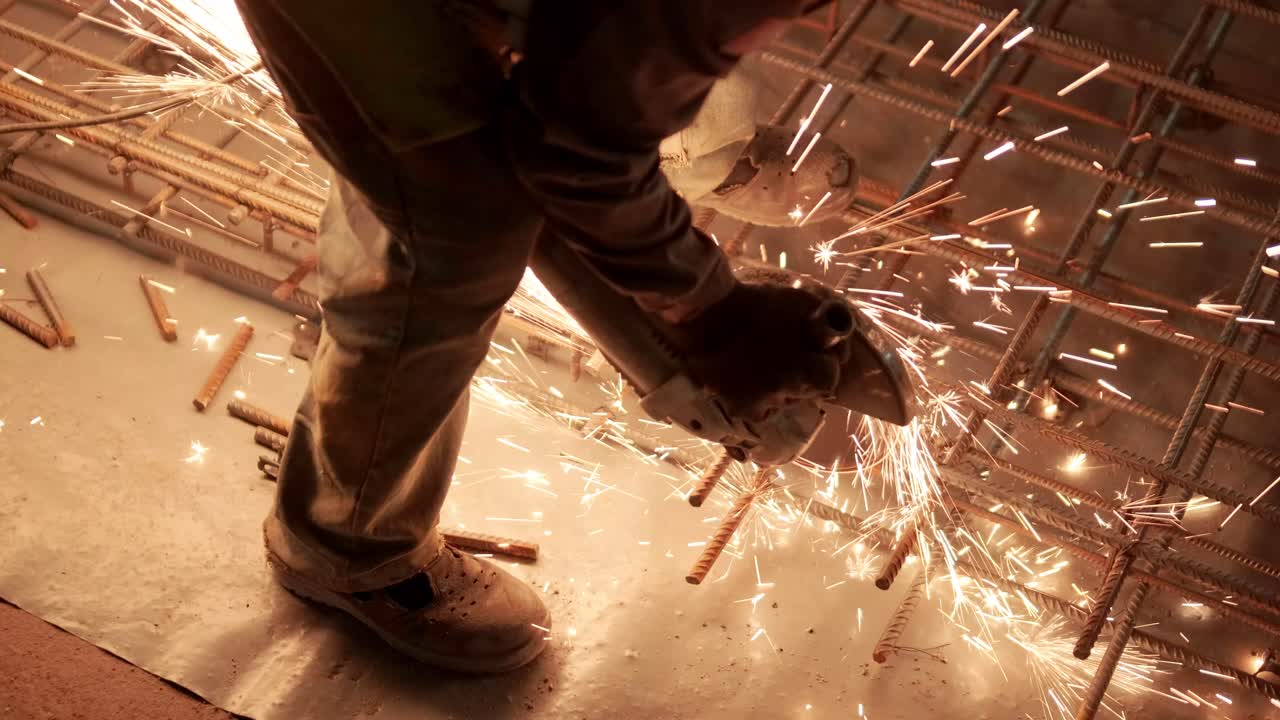 Industrial professional worker is cutting metal rebar with a circular saw. Construction of a factory, hangar