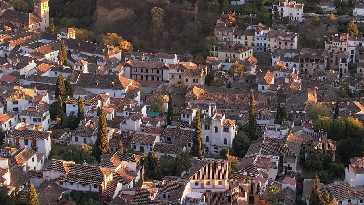 Vistas de Granada al atardecer muestran tejados y árboles en el paisaje español.