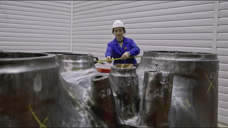 female engineer inspecting large metal components in a factory