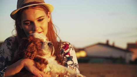 stunning hd footage of a white caucasion girl with a knitted hat and red lipstick holding a dog cavalier king charles spaniel in her arms, hugging and caressing it