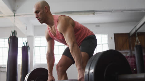 caucasian male trainer working out with barbell at the gym