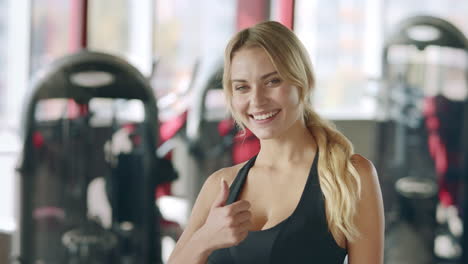 Retrato-De-Una-Entrenadora-Femenina-Mostrando-Un-Gesto-Con-El-Pulgar-Hacia-Arriba-En-El-Gimnasio.