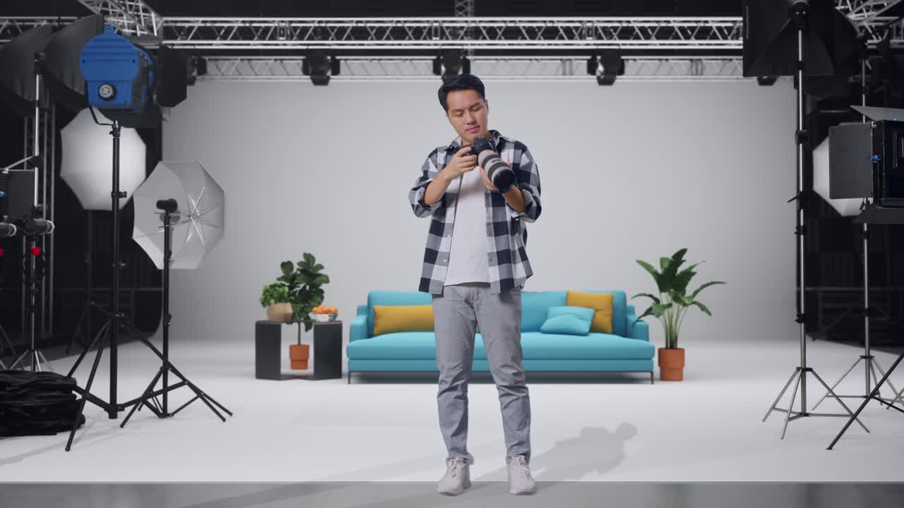 Full Body Of Asian Photographer Using A Camera Taking Pictures And Flexing His Bicep While Standing In The Studio