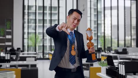 businessman holding trophy, thumbs down