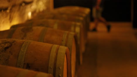 rows of wine barrels in a dimly lit cellar