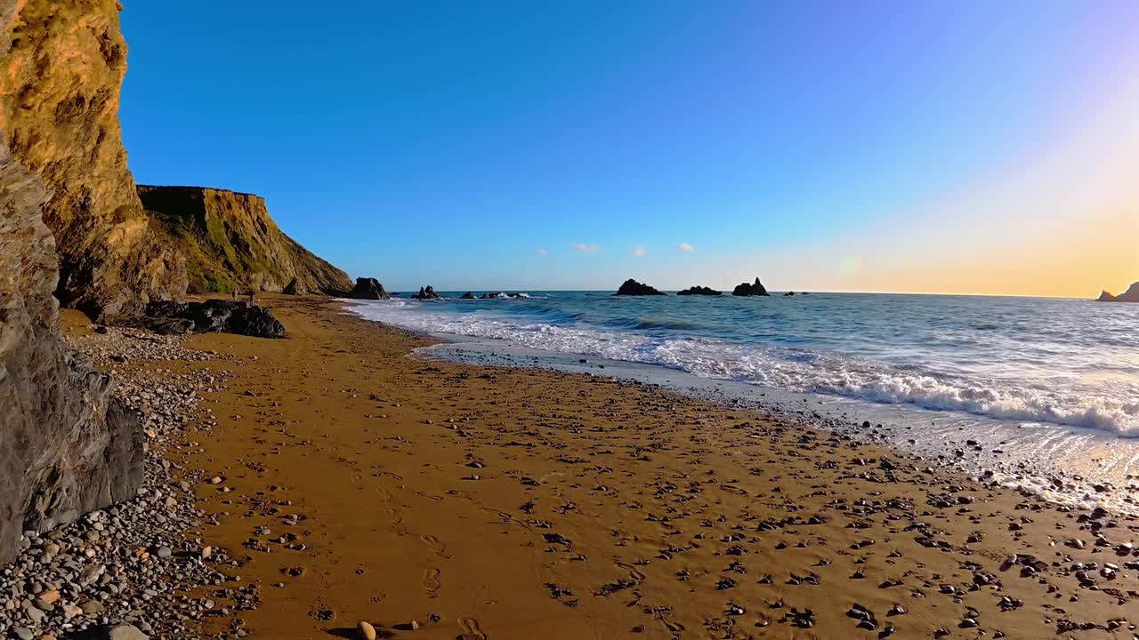Golden sands blue winter sky and incoming waves beach at golden hour Waterford Ireland