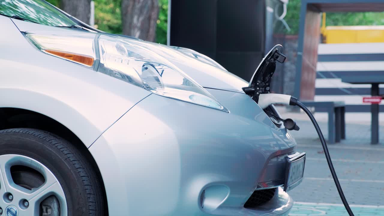 proceso de reabastecimiento de combustible de un automóvil eléctrico. un disparo debajo de la escotilla donde se carga el automóvil ecológico eléctrico. la escotella de carga del automóvil eléctrico se abre automáticamente. una mano masculina inserta un automóvil erecto