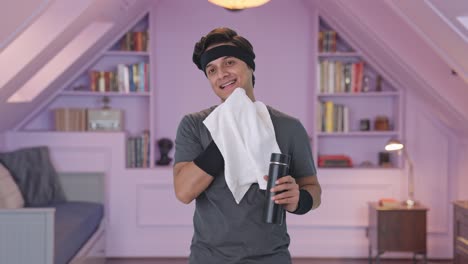 hombre indio feliz limpiando sudor y bebiendo agua después del ejercicio