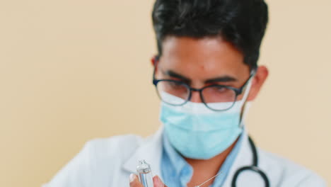 indian young doctor man holding syringe needle and ampoule with liquid medicine treatment injection