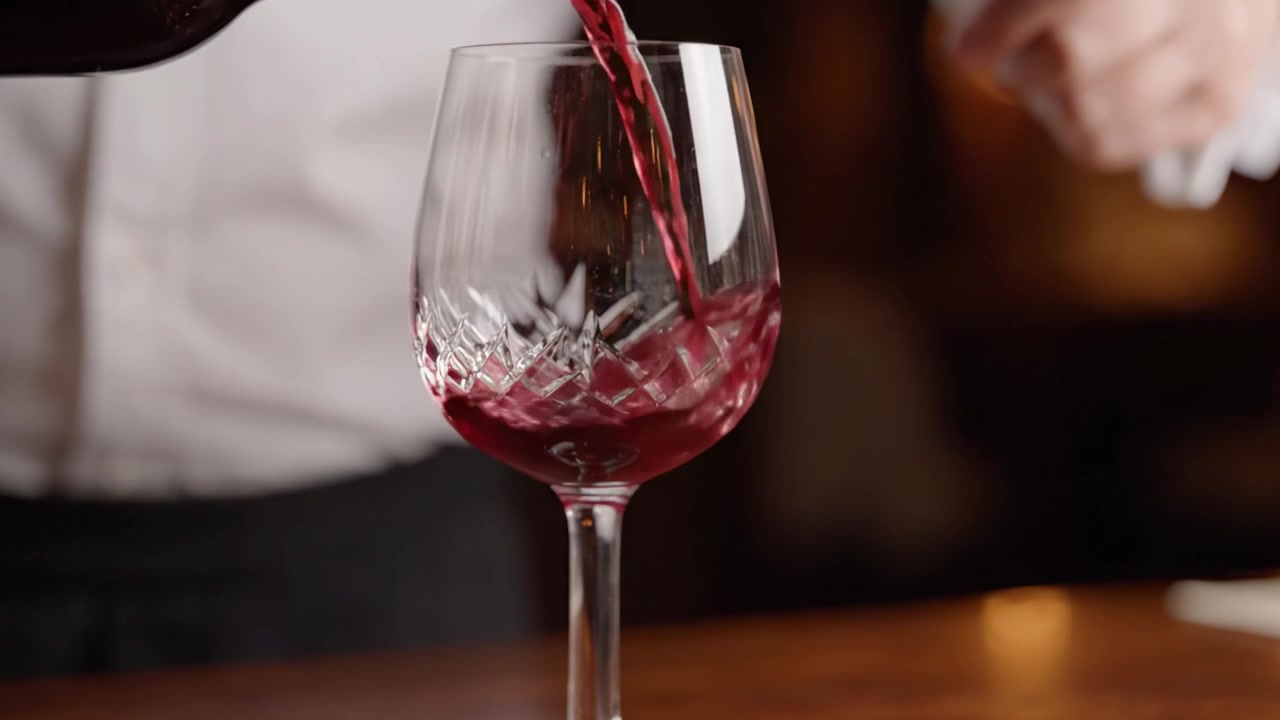 Una transizione elegante: versare vino in un bicchiere di cristallo cattura l'essenza della raffinatezza e del piacere in un'esperienza culinaria di lusso.