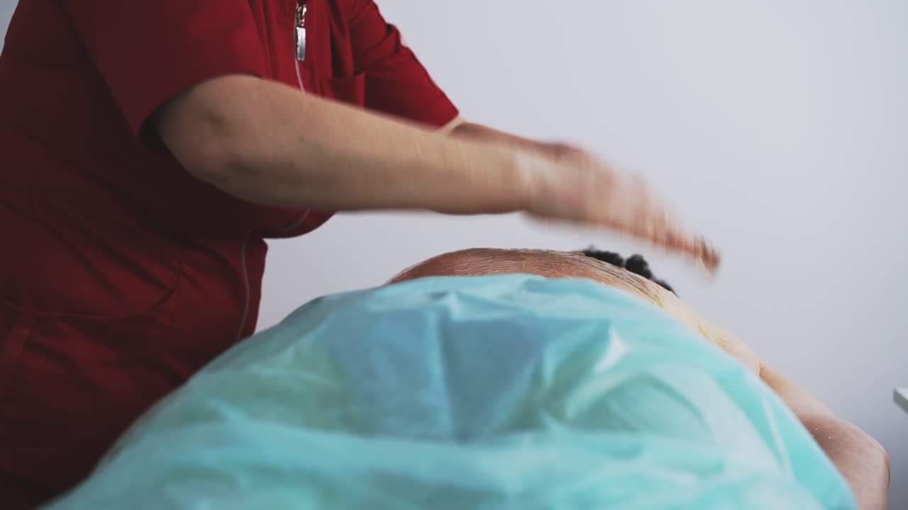 el terapeuta masajea con miel la espalda de una mujer de mediana edad.