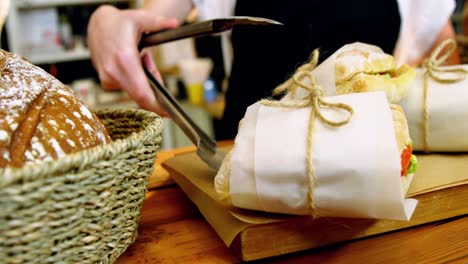 mid-section of waitress holding sandwich with a tongs