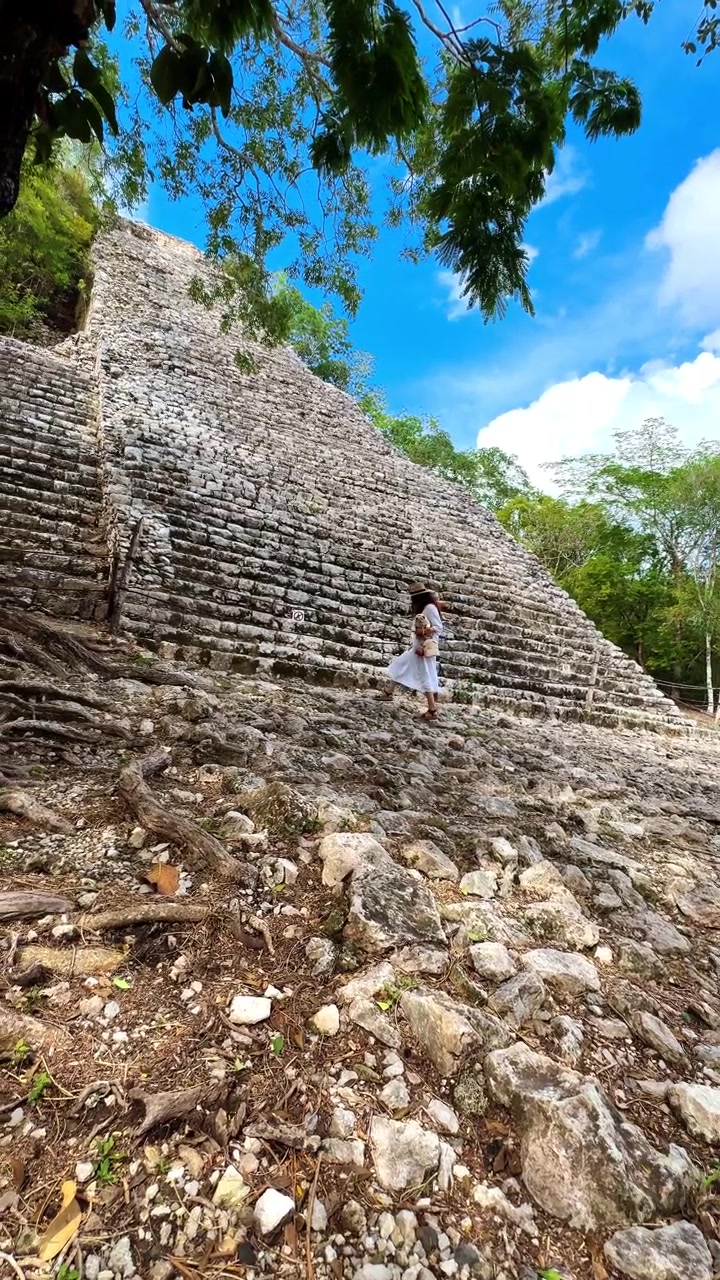 Tulum, Messico, 1 agosto 2025: Antiche scale di piramide in pietra in un ambiente di foresta tropicale. Vista dal basso di rovine in stile Maya con gradini in pietra che salgono sotto un cielo azzurro.