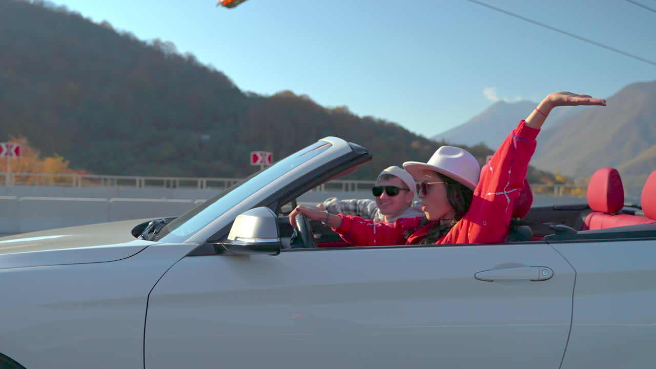 커플 이 컨버터블 로 경치 좋은 드라이브 를 즐기고 있다