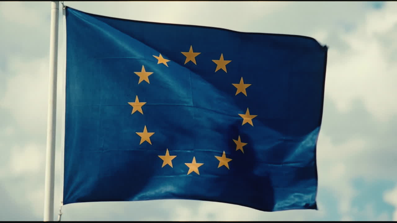 Bandiera dell'Unione Europea che sventola al vento contro un cielo nuvoloso.