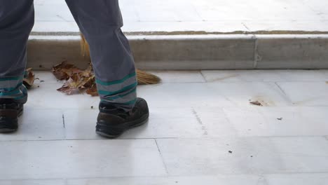 worker sweeping leaves on the sidewalk