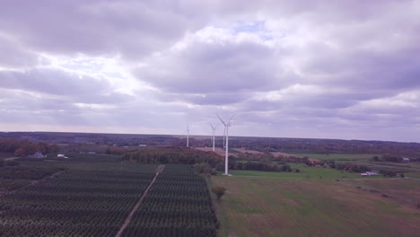 aerial footage of drone moving forward towards wind farm with giant wind turbines spinning creating renewable energy