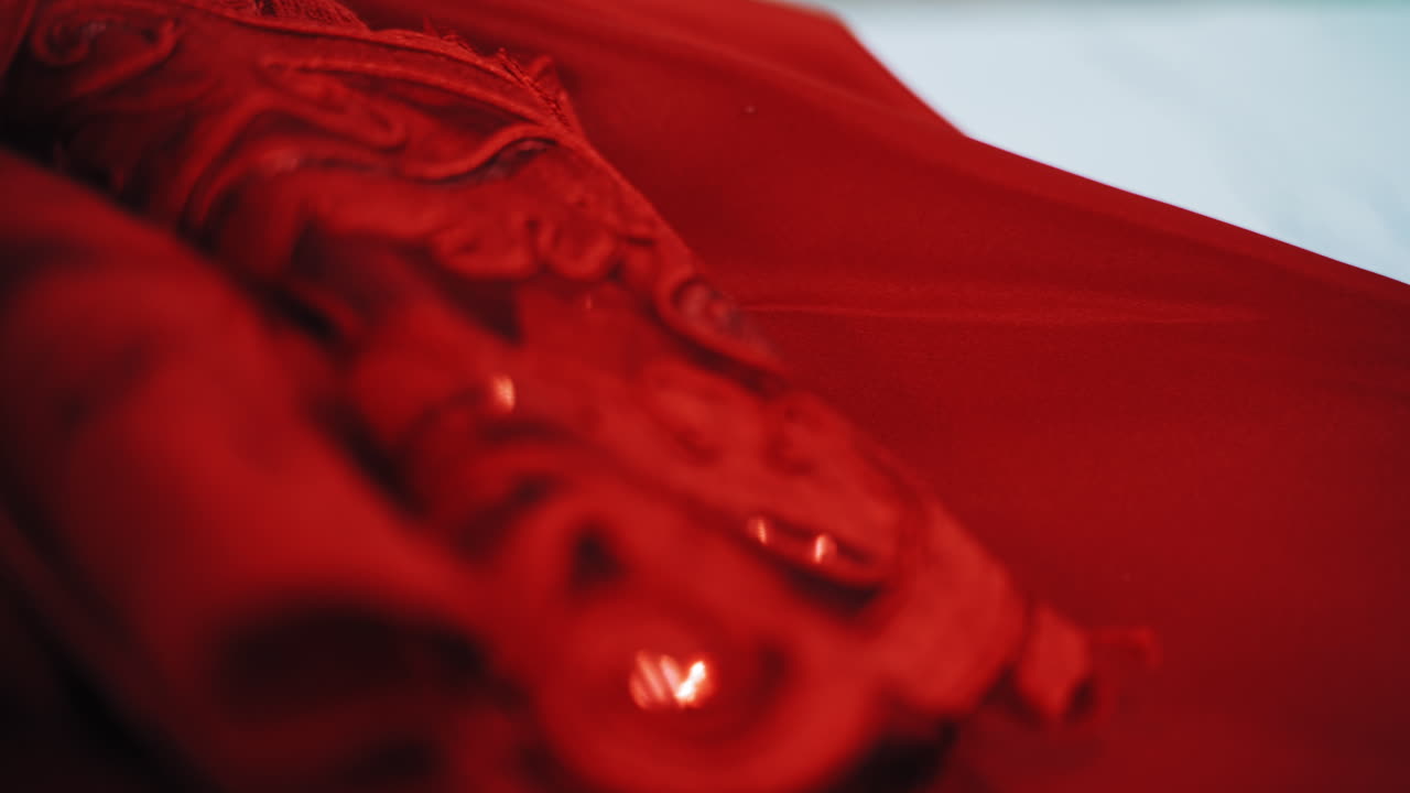 White sheets of papers with stylish sketches painted on the table. A lot of creative works of a fashionable designer and red material for seamstress in atelier.