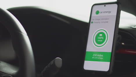 primer plano del conductor en el coche con manos libres unidad para teléfono móvil con aplicación de monitoreo del nivel de la batería