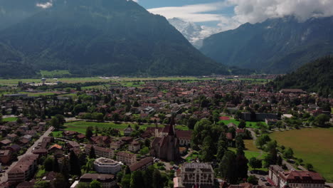 Umkreist-Die-Stadt-In-Den-Schweizer-Alpen,-Das-Tal-Von-Interlaken-–-Luftaufnahme-Von-Grünen-Wiesen-Und-360-Grad-Blick-Auf-Die-Stadt