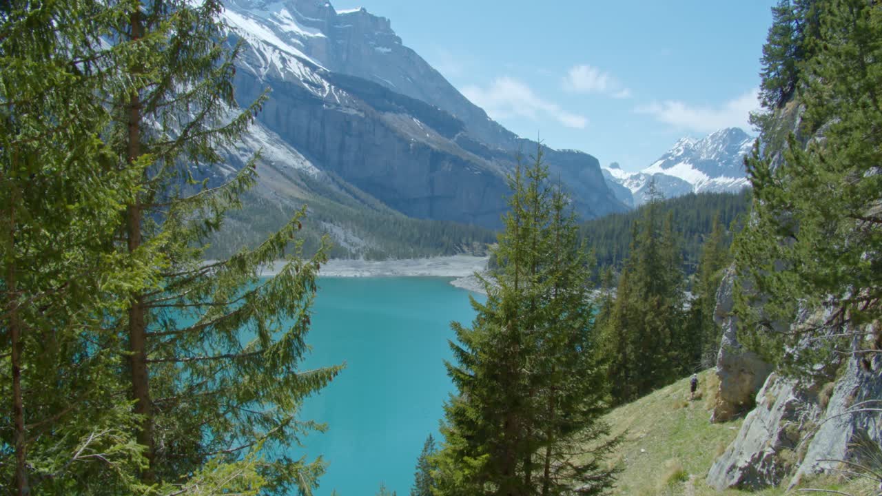 alcanzando su punto máximo desde un lugar alto, detrás de los árboles, en un hermoso lago azul frío rodeado por los alpes