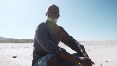 Senior-man-sitting-on-the-sand-at-the-beach