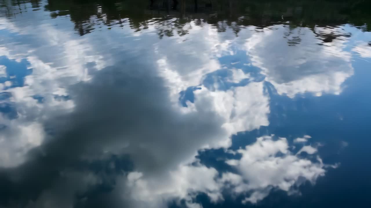 Pantulan awan yang berkilauan bergeser di kolam, angin sepoi-sepoi menyebabkan riak dan garis pepohonan memantul