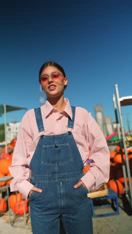 teenager in overalls and pink shirt at a pumpkin patch