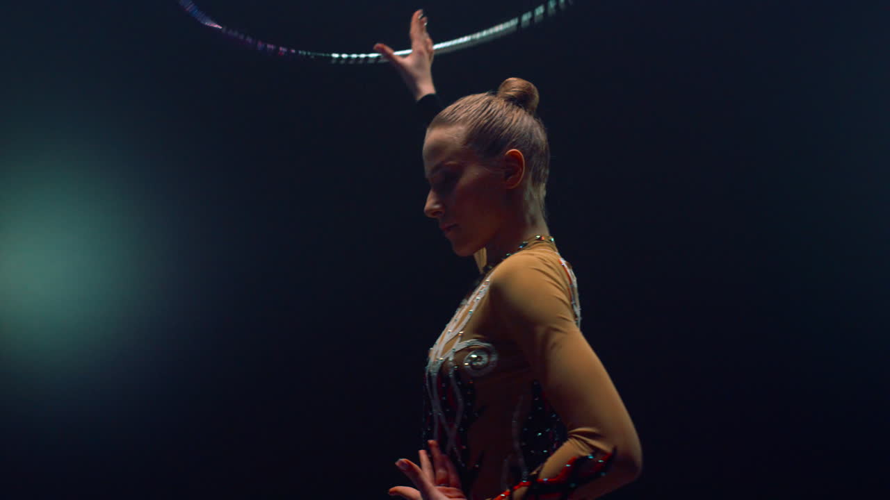 Donna flessibile che posa per la telecamera durante un'esibizione con l'hula hoop. Atleta che si allena.