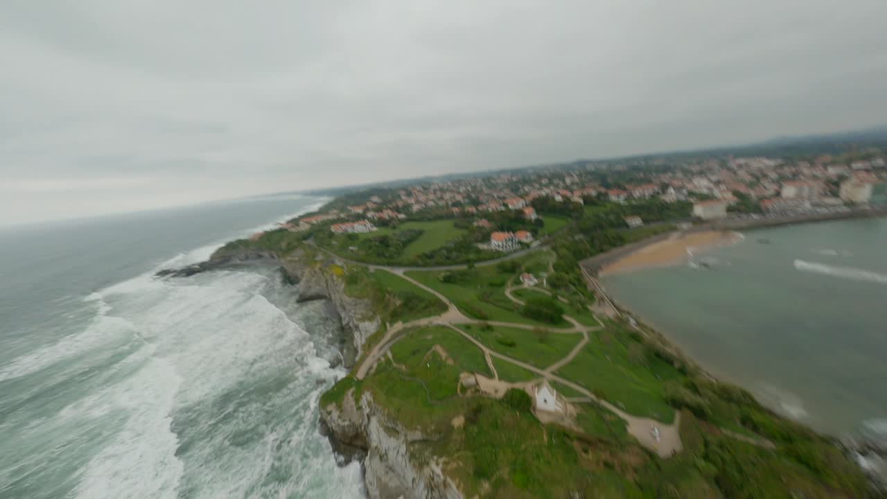 Rugged cliffs and coastline of Saint-Jean-de-Luz, town buildings, beach, and Atlantic Ocean waves, France. Aerial drone FPV, UAV