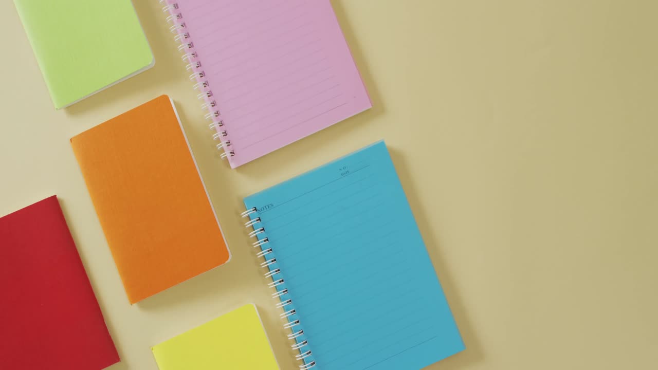 video de composición con cuadernos coloridos en superficie amarilla