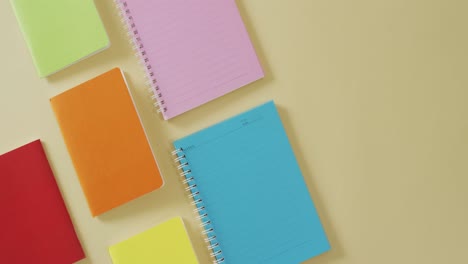 video of composition with colorful notebooks on yellow surface