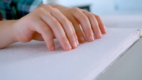 blind schoolboy hands reading a braille book at desk in classroom at school 4k