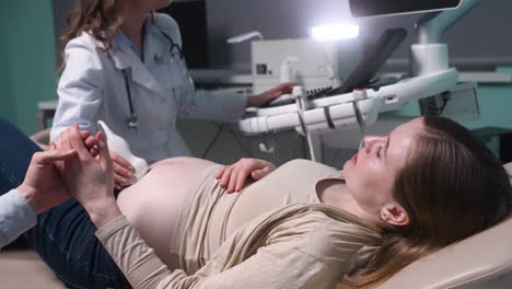 Mujer-Embarazada-Con-Ecografía-En-La-Oficina-Del-Ginecólogo-Mientras-Ama-A-Su-Esposo-Sosteniendo-Su-Mano-11