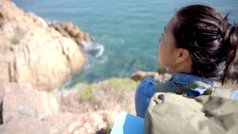 hiking with backpack, woman enjoying scenic ocean view from mountain cliff