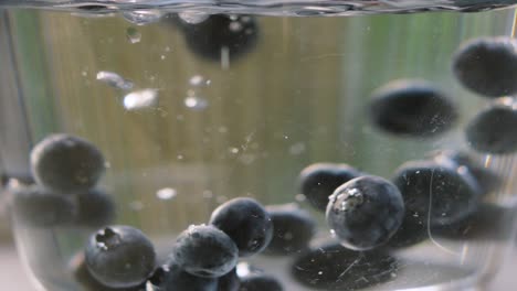 blueberries falling into bowl with bubbles rising as they gently rise back up. ripe fruit high in magnesium and fibre. healthy eating food footage