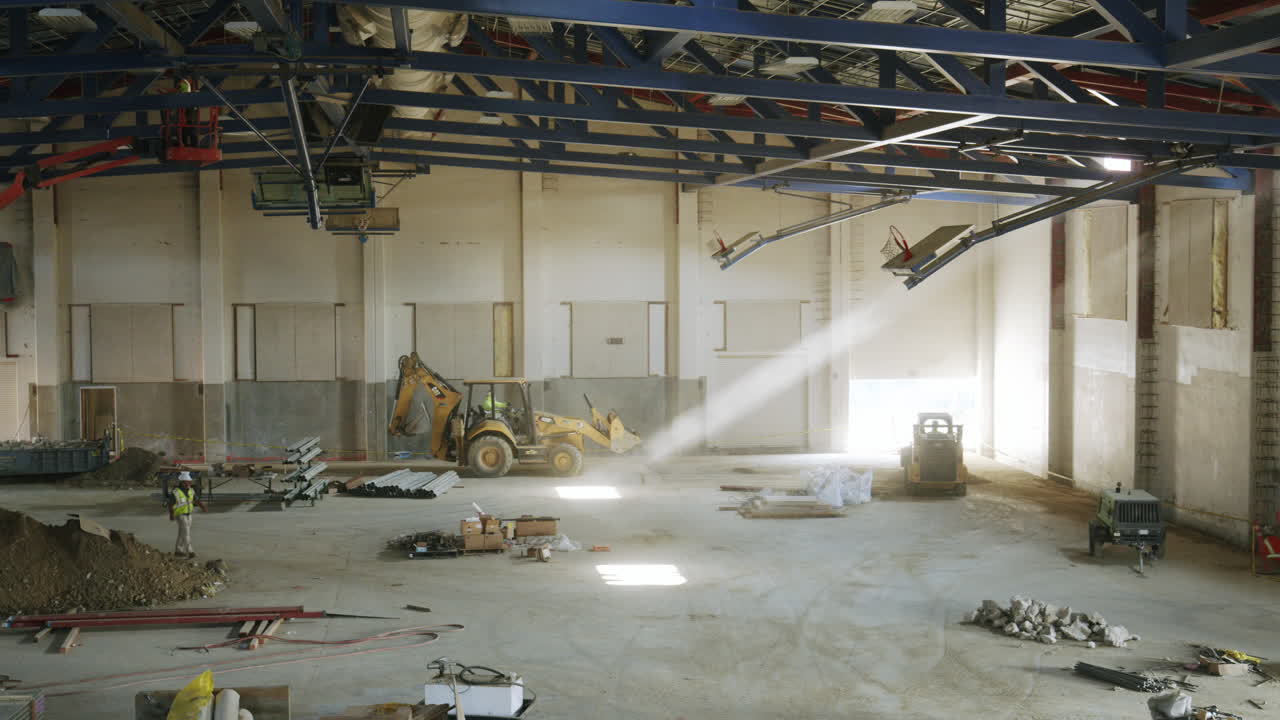 Large Interior Space of a Warehouse Under Construction with Heavy Equipment and Sunlight