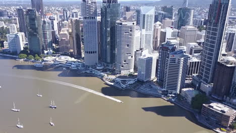 Toma-Aérea-Inclinada-De-Edificios-Altos-De-La-Ciudad,-Motos-Acuáticas-Y-Veleros-A-Lo-Largo-Del-Río-Brisbane,-Queensland