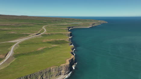 cliff in north of iceland with coastal road and green grass