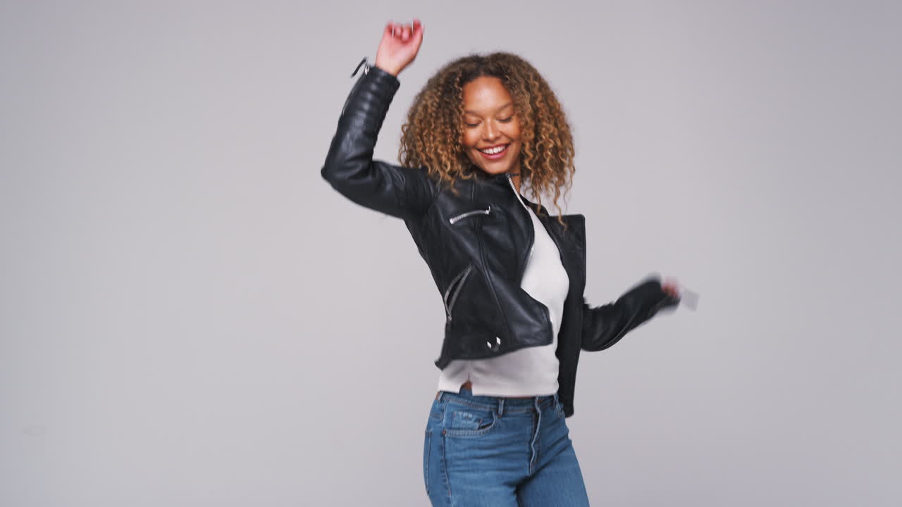 Wide Angle Studio Shot Of Young Woman Wearing Leather Jacket Dancing In Slow Motion