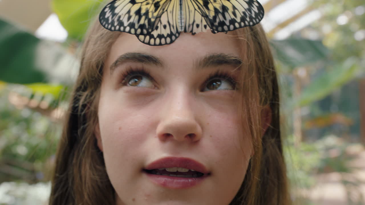 hermosa chica sonriendo con mariposa en la cara aleteando alas divirtiéndose con la vida silvestre en el zoológico de conservación de la naturaleza 4k