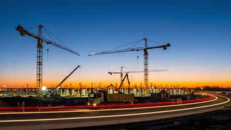 night construction site with cranes and light trails