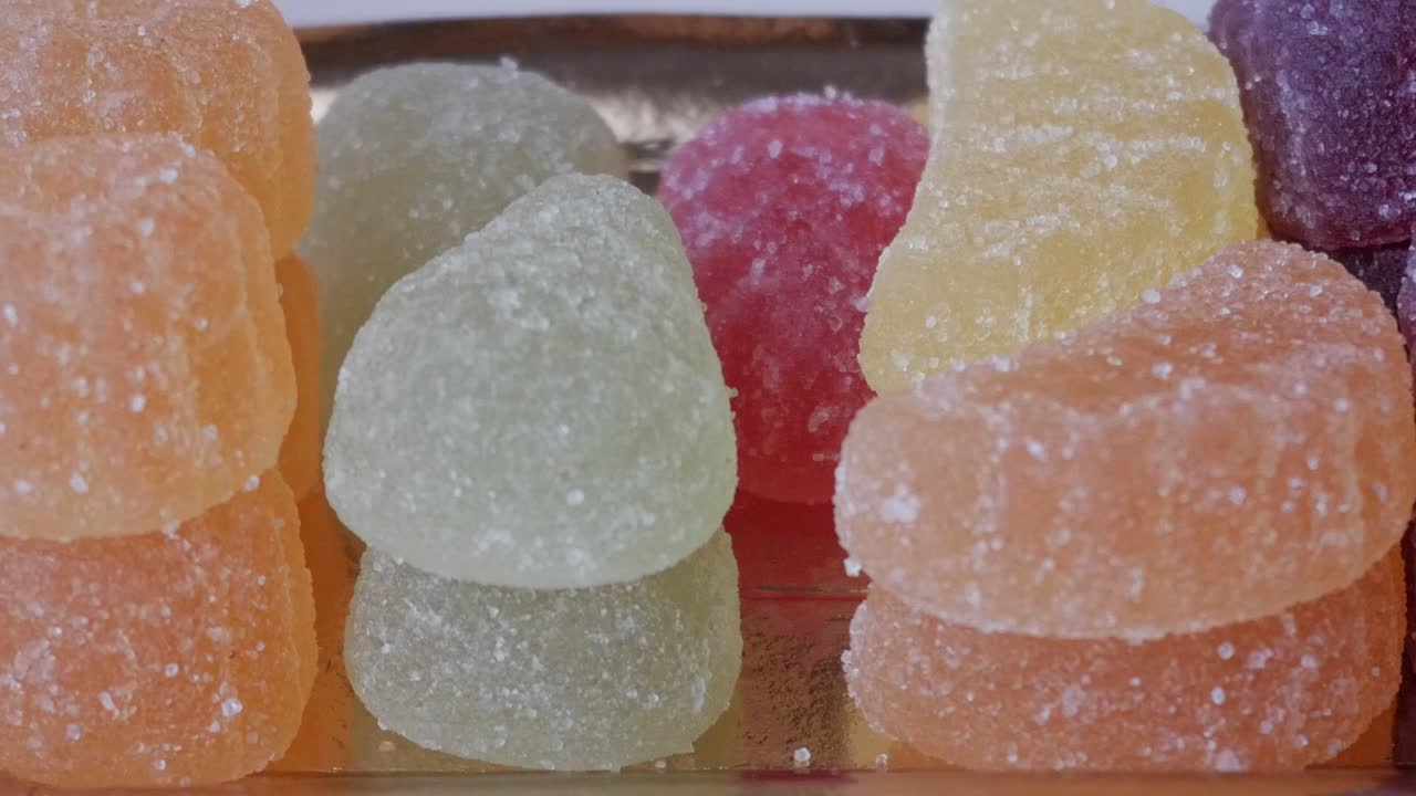 Smooth pan right over a golden tray filled with colorful sugar-coated jelly candies in various shapes