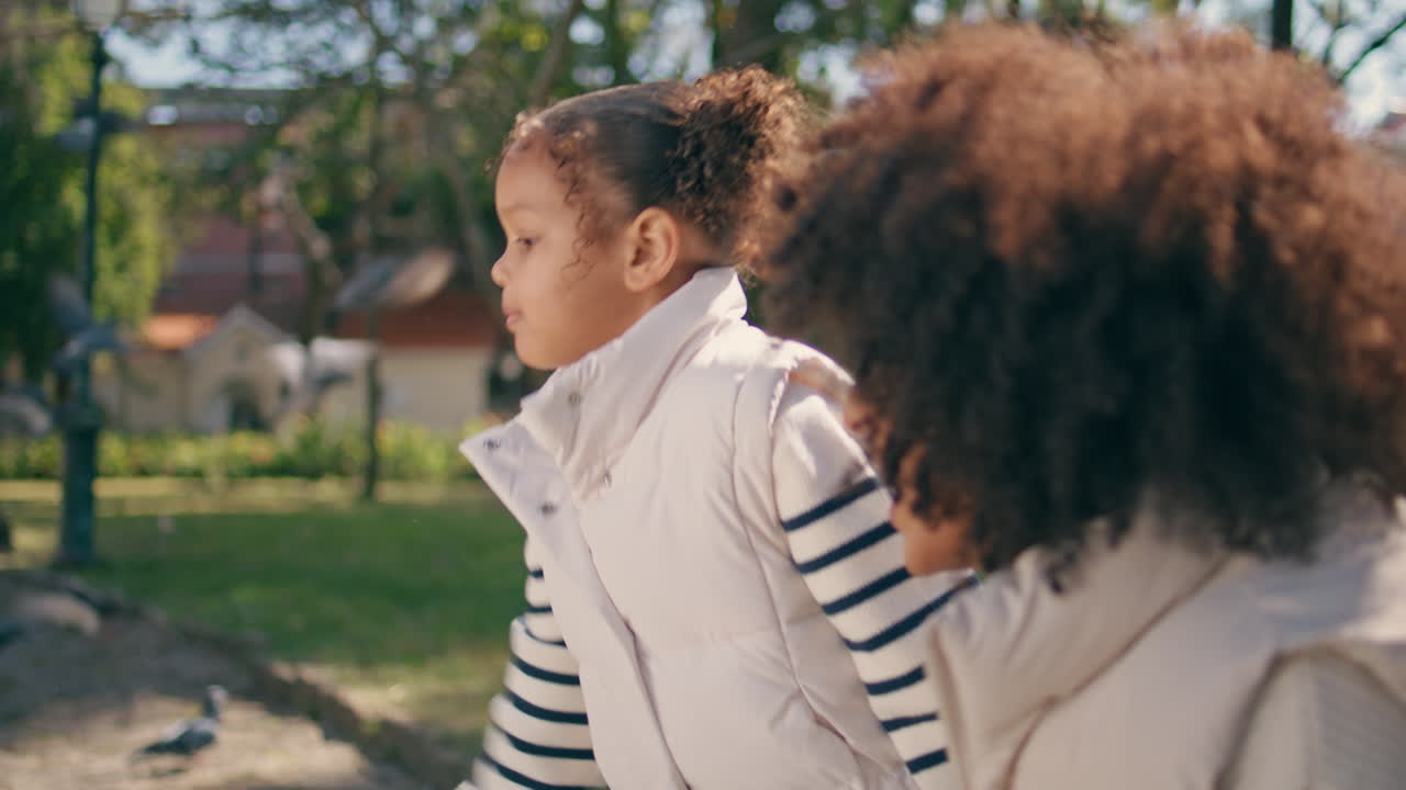사니 파크에서 엄마와 함께 비둘기를 먹이는 귀여운 소녀. 재미있는 아이