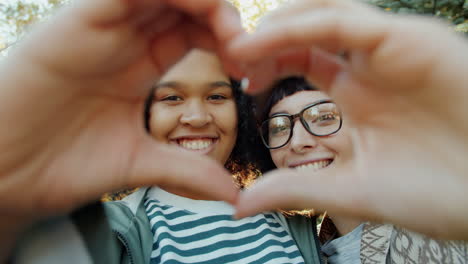 two friends making a heart shape with hands