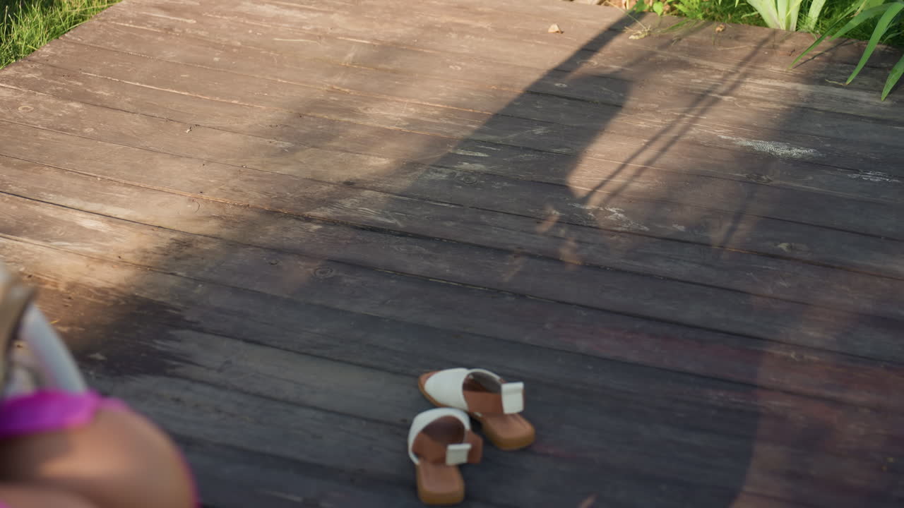 Woman Enjoys Outdoors, Female Relaxes Barefoot On Sunny Patio, Woman Unwinds Outdoors Without Shoes On Bright Summer Day, Lady Spends Peaceful Leisure Time Barefoot Outside On Sunlit Porch Deck